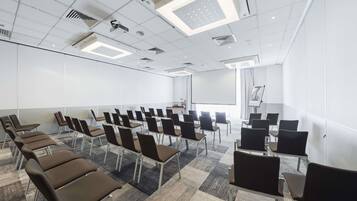 A conference room with rows of chairs, a projector screen, and a large window.