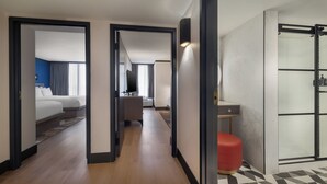 Pasillo de hotel con una cama, un escritorio y zona de ducha.