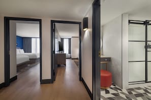 Pasillo de hotel con una cama, un escritorio y zona de ducha.