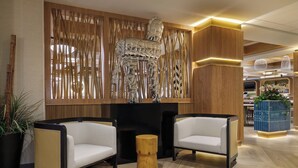 Un hall d’entrée moderne avec deux canapés blancs, un mur d’accent en bois et une sculpture décorative.