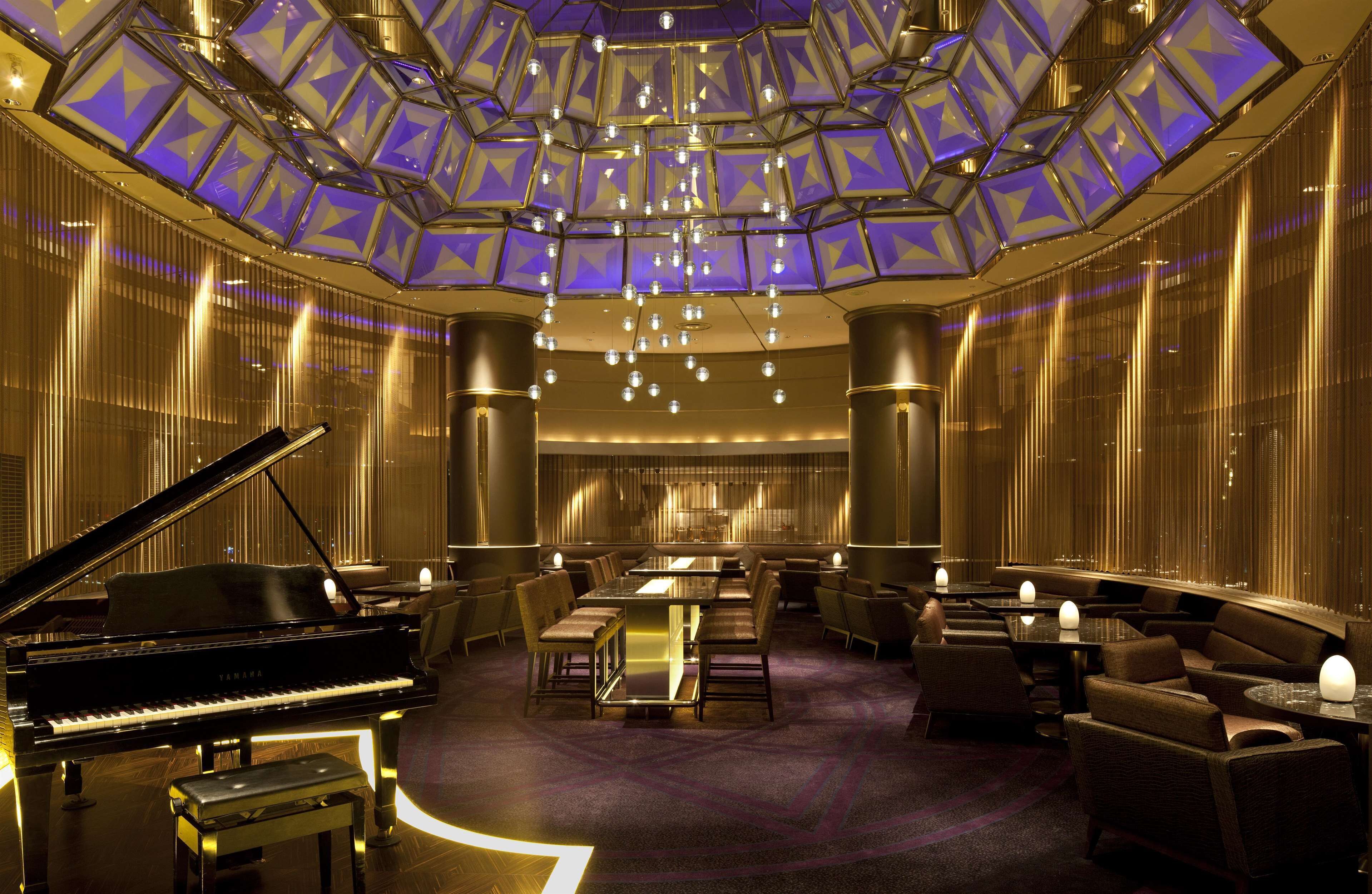 A luxurious lobby with a grand piano, plush seating, and a modern chandelier.