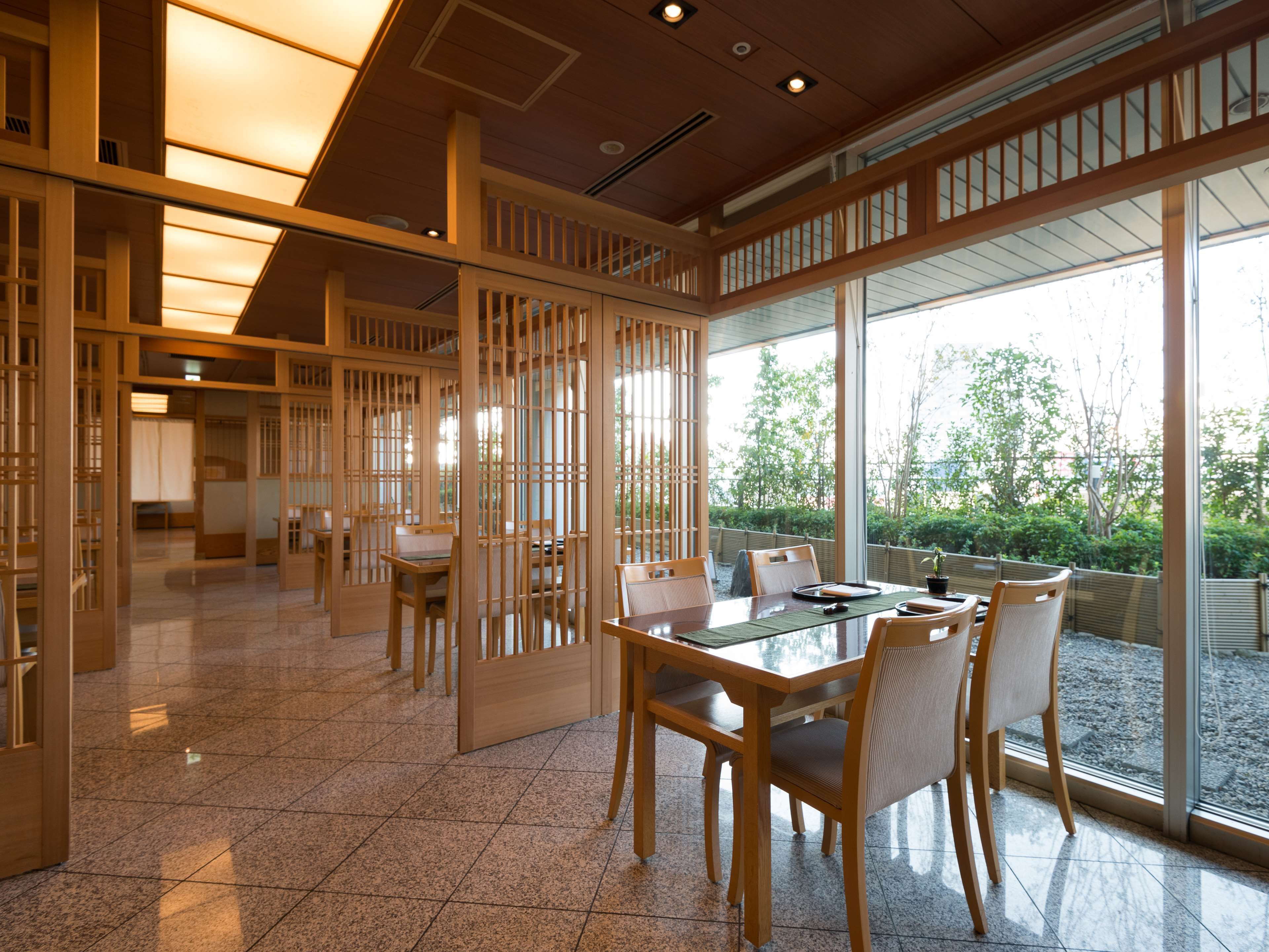 Una habitación tradicional japonesa con suelo de tatami, puertas correderas y vistas al jardín.