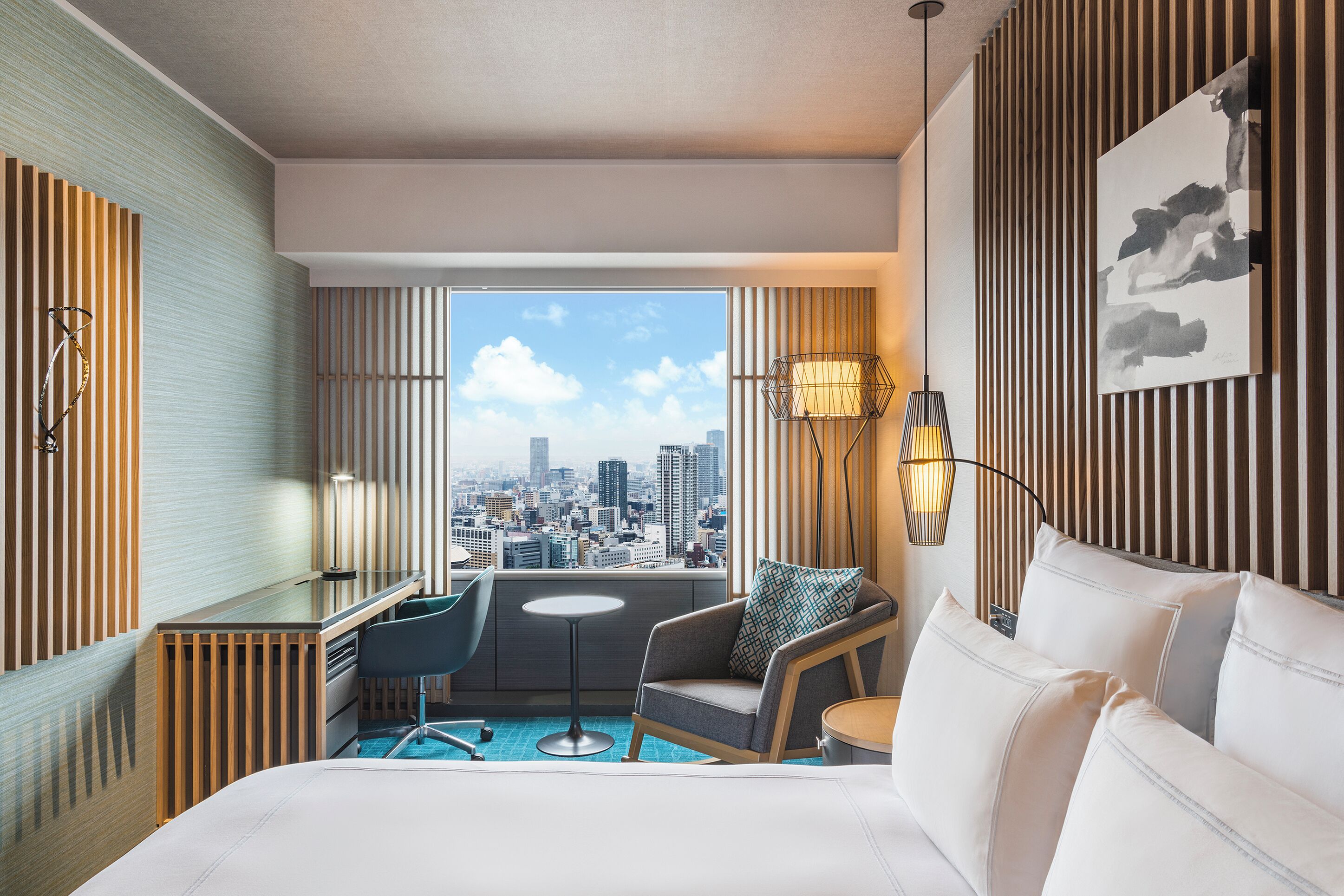 Habitación de hotel con vistas a la ciudad, un escritorio, una silla, una cama y una mesita.