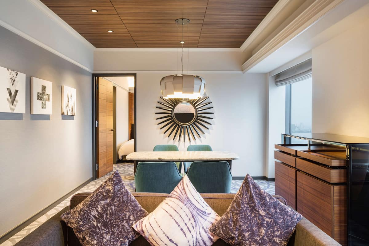 A modern dining area with a wooden ceiling, a round mirror with a sunburst design, and a dining table with chairs.