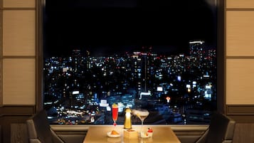 A table with a cityscape view, a cocktail, and a dessert.