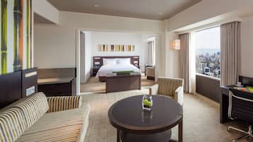 Une chambre d’hôtel avec un lit, un canapé, une table à manger et une vue sur la ville.