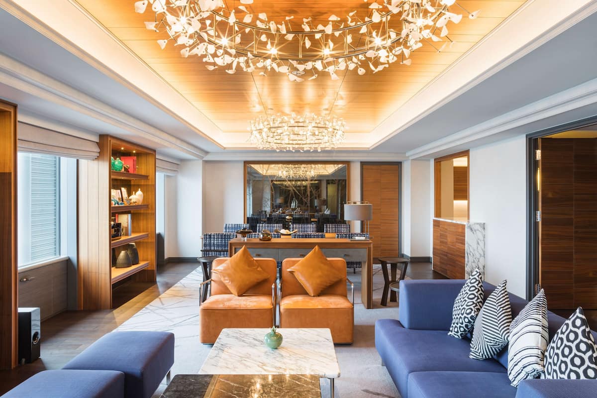 A modern living room with a sofa set, a coffee table, and a chandelier.