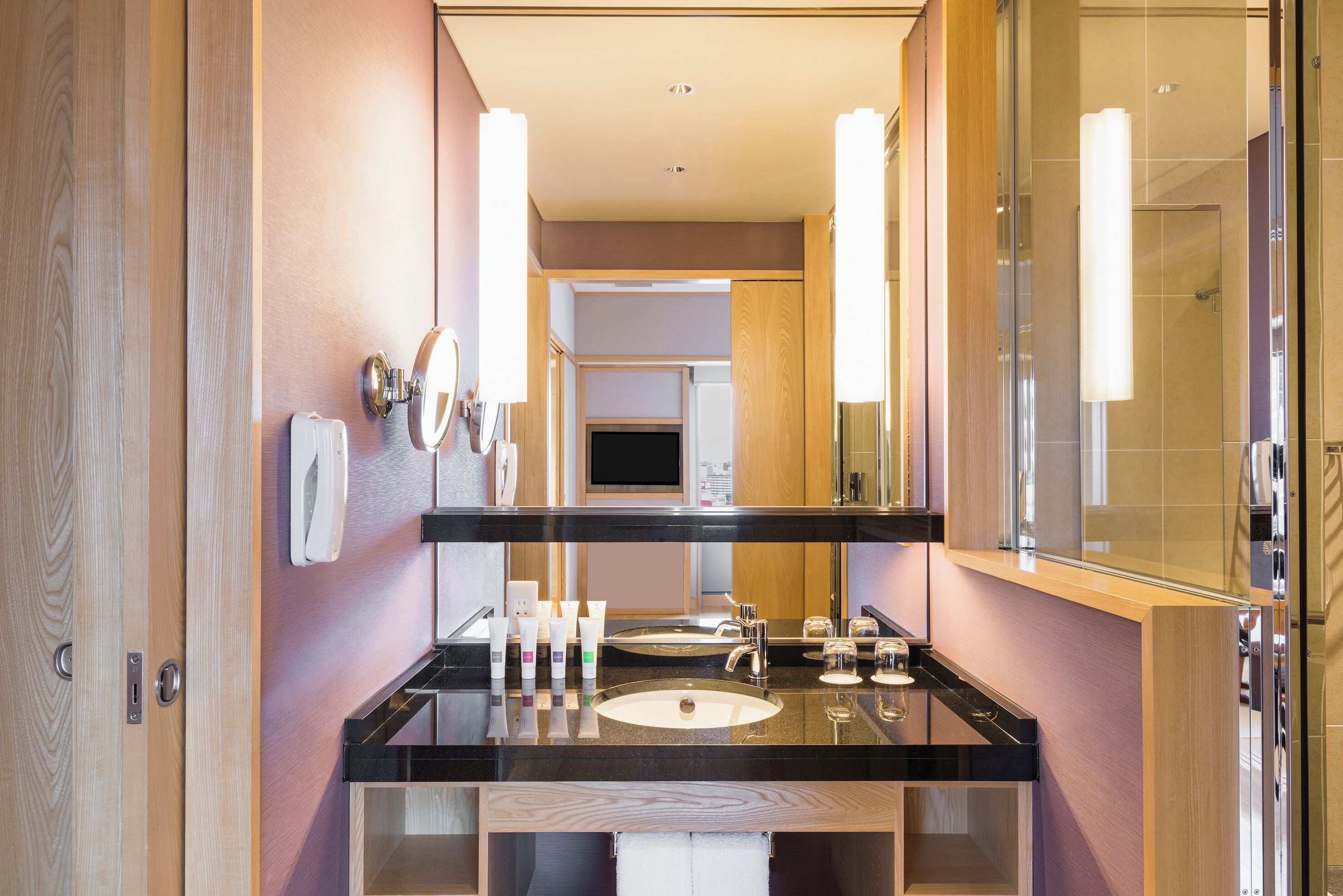 A modern bathroom with a black countertop, two sinks, a large mirror, and a glass shower enclosure.
