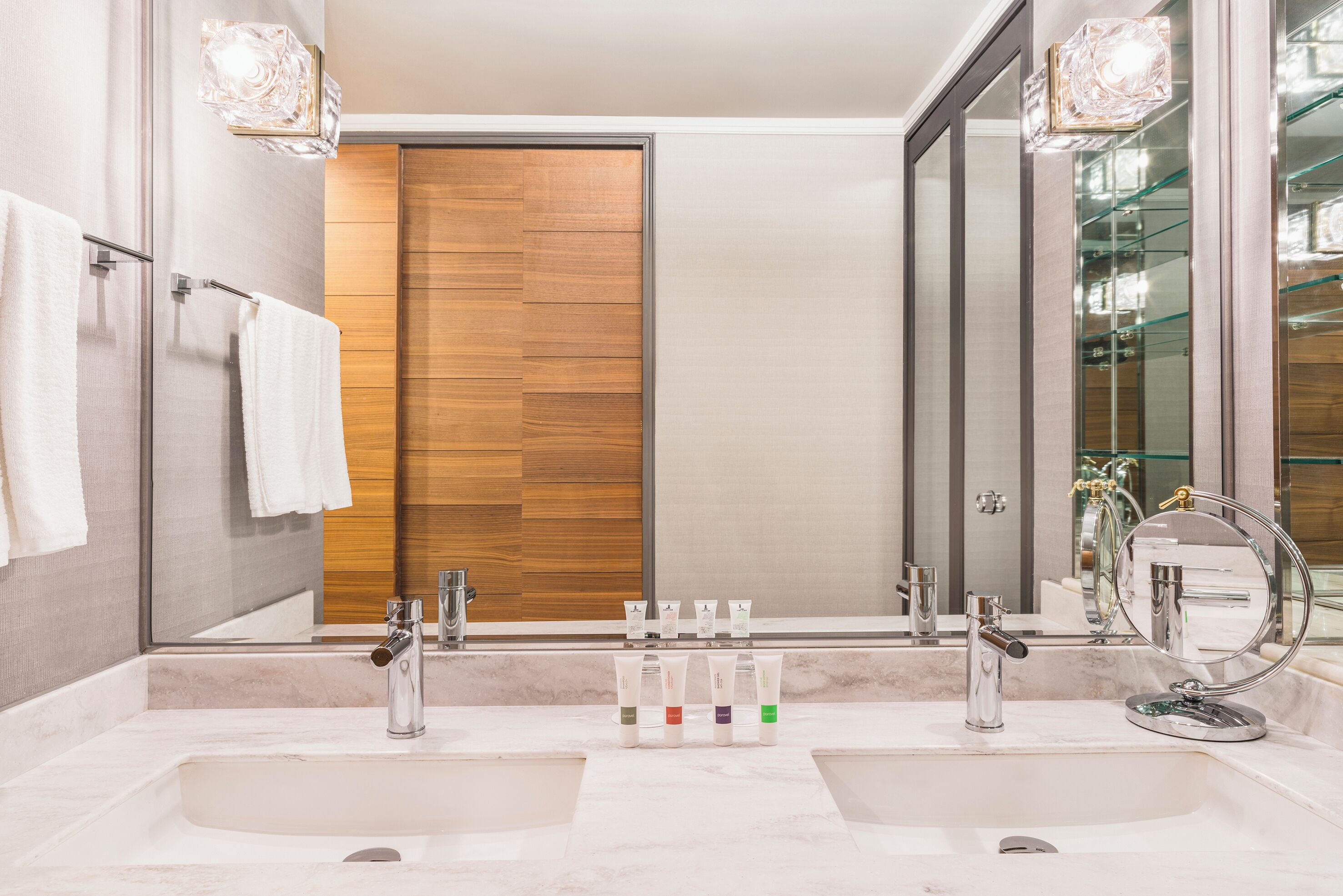 Une salle de bain moderne avec deux lavabos, une porte en bois et un grand miroir.