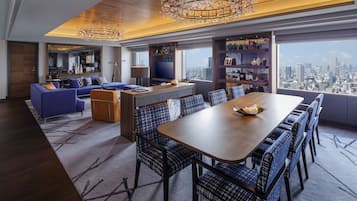 A modern living room with a large dining table, blue upholstered furniture, and a city view through large windows.