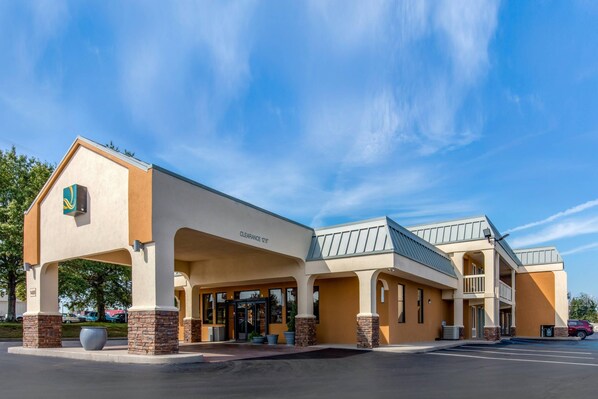 A hotel with a beige facade, a covered entrance, and a parking lot.