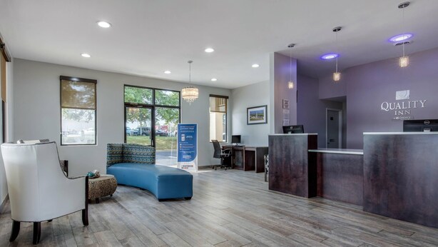 A reception area with a blue sofa, a reception desk, and a large window offering a view of the outdoors.