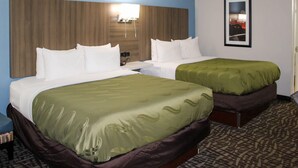 A hotel room with two beds, a headboard, a bedside table, and a framed picture on the wall.