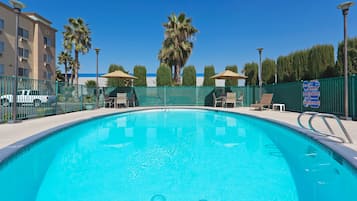 Una piscina al aire libre, sillones reclinables de piscina