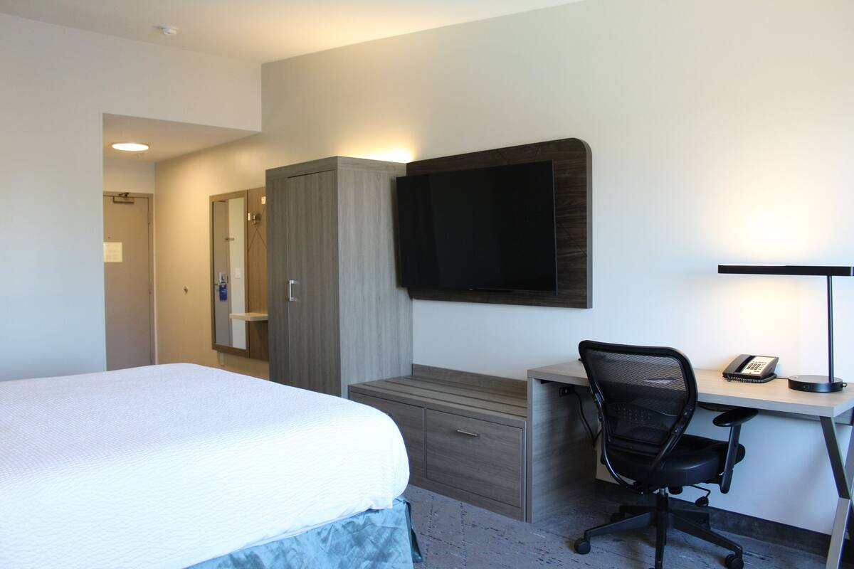 Een hotelkamer met een bed, een bureau met stoel, een flatscreen televisie en een bureaulamp.