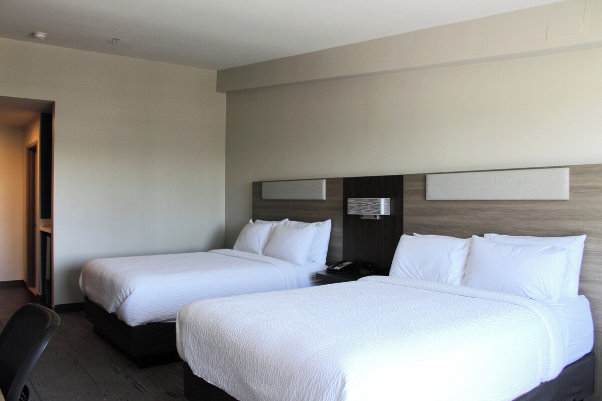 Une chambre d’hôtel avec deux lits simples, un bureau et une chaise.