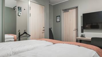 Et hotelværelse med to senge, et skrivebord, et fjernsyn og et spejl.