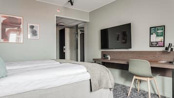 Habitación de hotel con cama, escritorio, silla, televisor y un cartel en la pared.