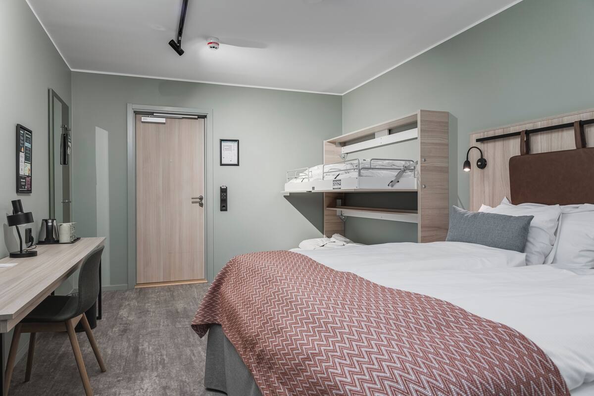 Un dormitorio con cama, escritorio, armario y puerta.
