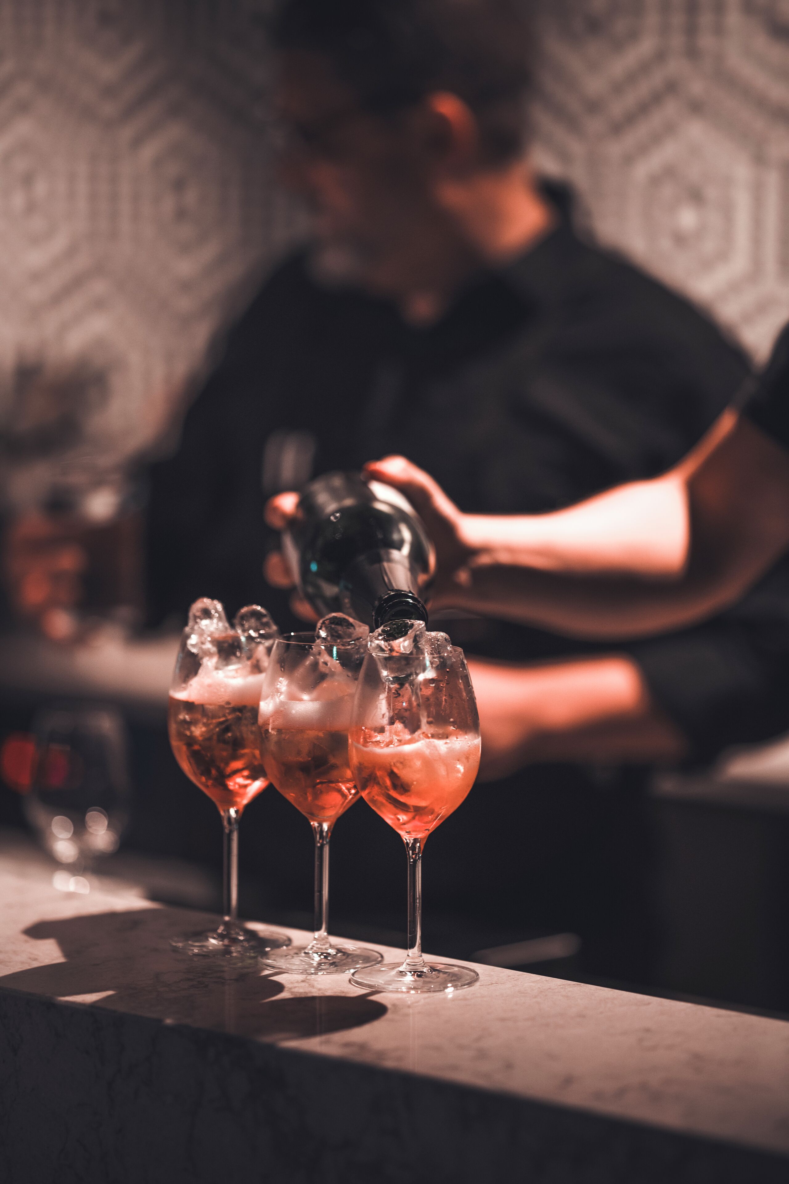 A bar setting with a bartender pouring a drink into a glass.
