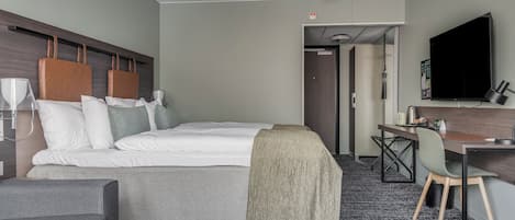 A hotel room with a bed, a desk, a chair, a television, and a coffee table.