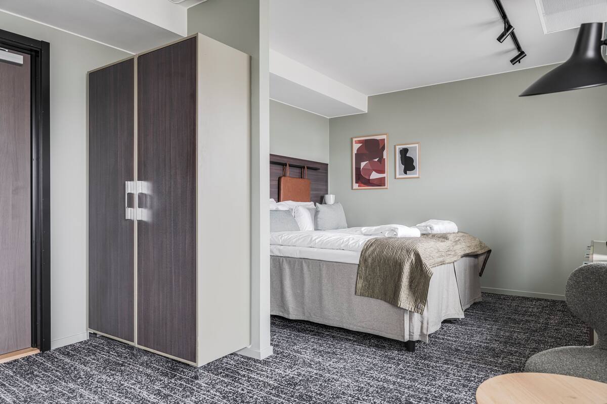 Una habitación de hotel con una cama, un armario, un escritorio y una silla.