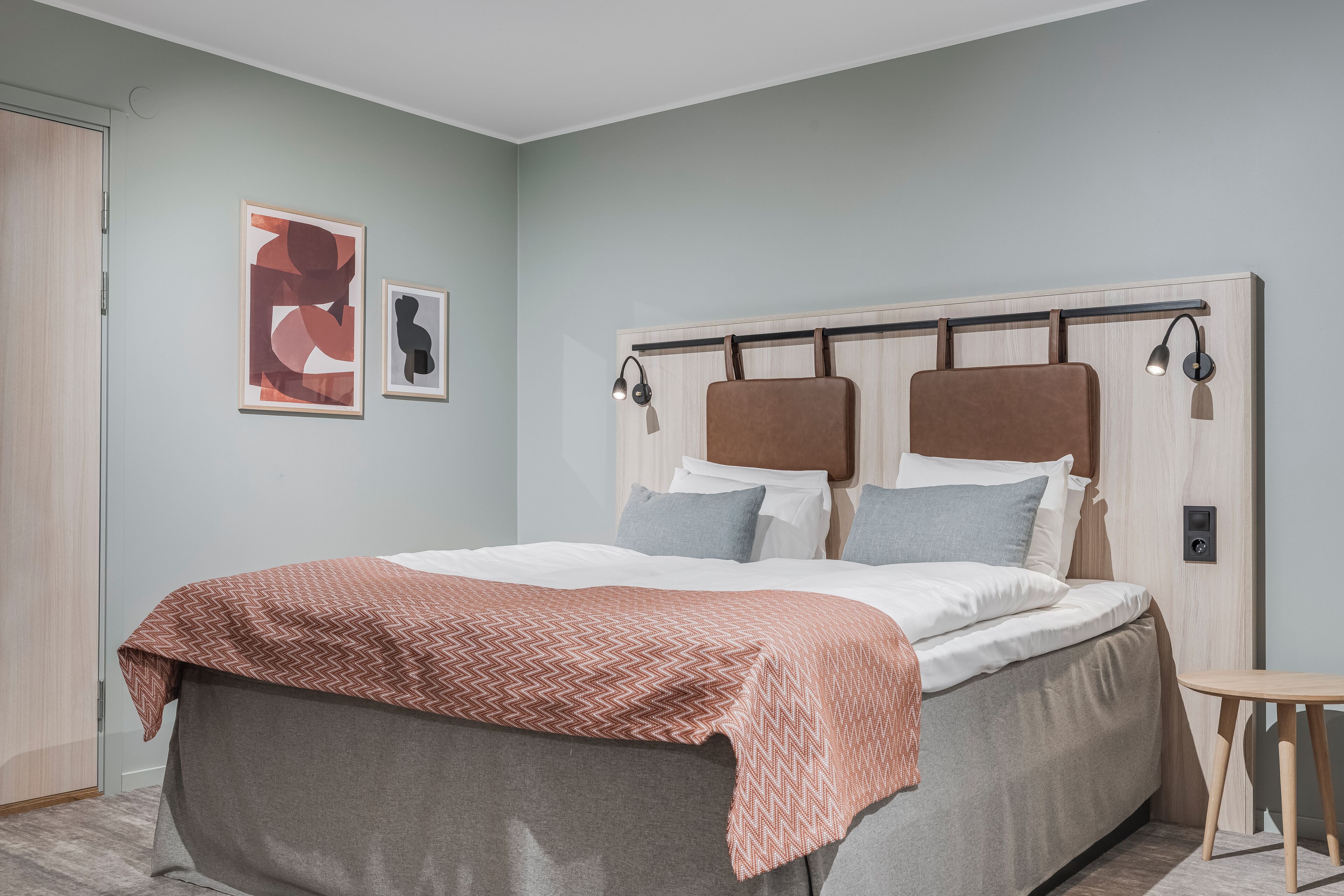A modern bedroom with a bed, a bedside table, and a wall-mounted lamp.