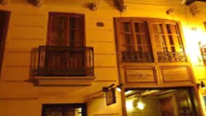 Edifici amb múltiples balcons, finestres il·luminades i una porta amb un rètol.