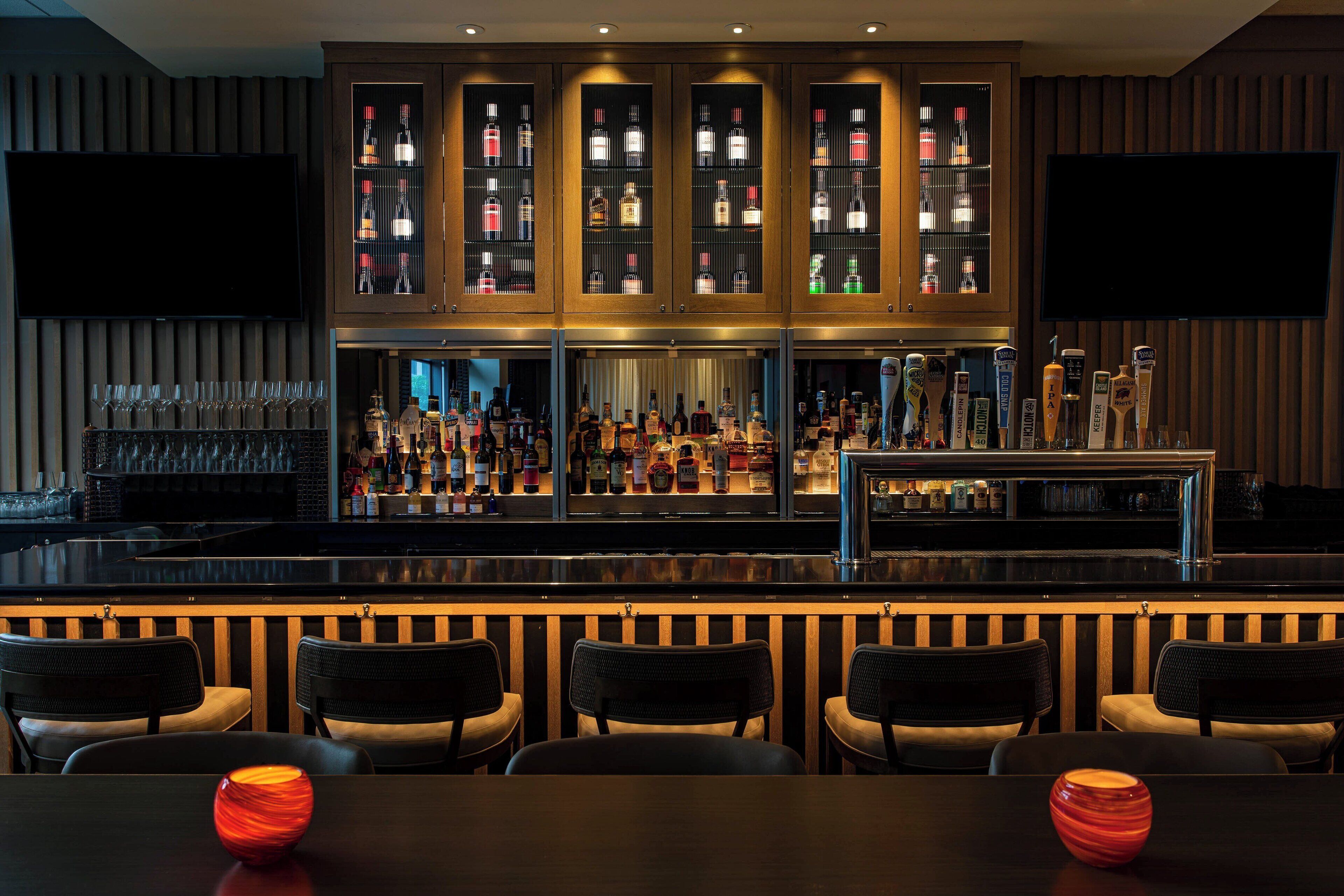 A bar area with multiple shelves of bottles, a counter, and bar stools.