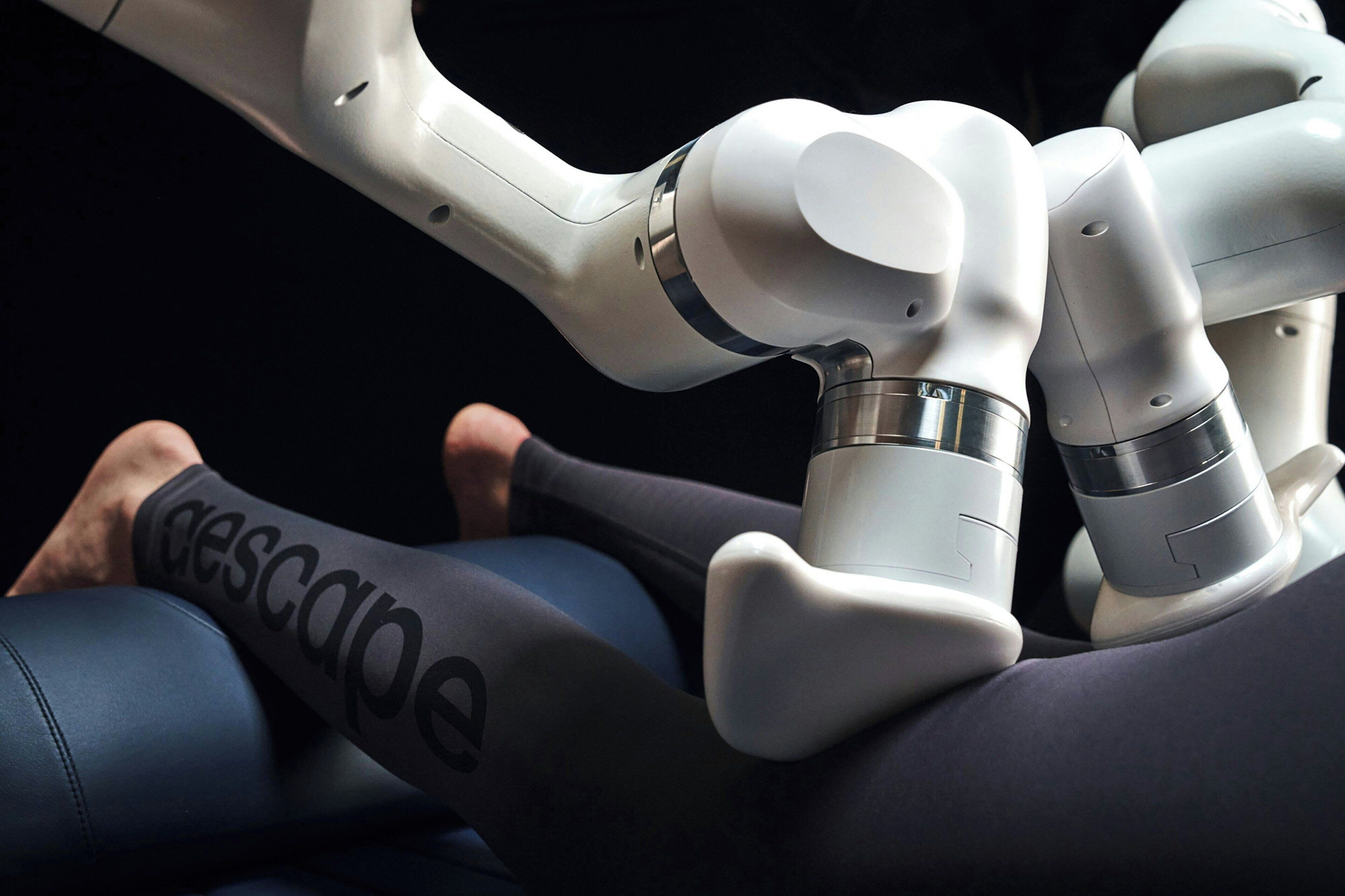 A robotic arm interacting with a person wearing a legged exoskeleton.