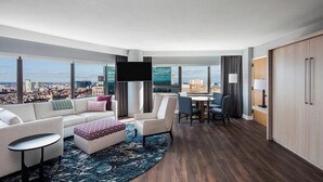 A modern hotel room with a large window offering a city view, a sofa, a coffee table, a dining area, and a flat-screen TV. - The Westin Copley Place, Boston, a Marriott Hotel (Boston)