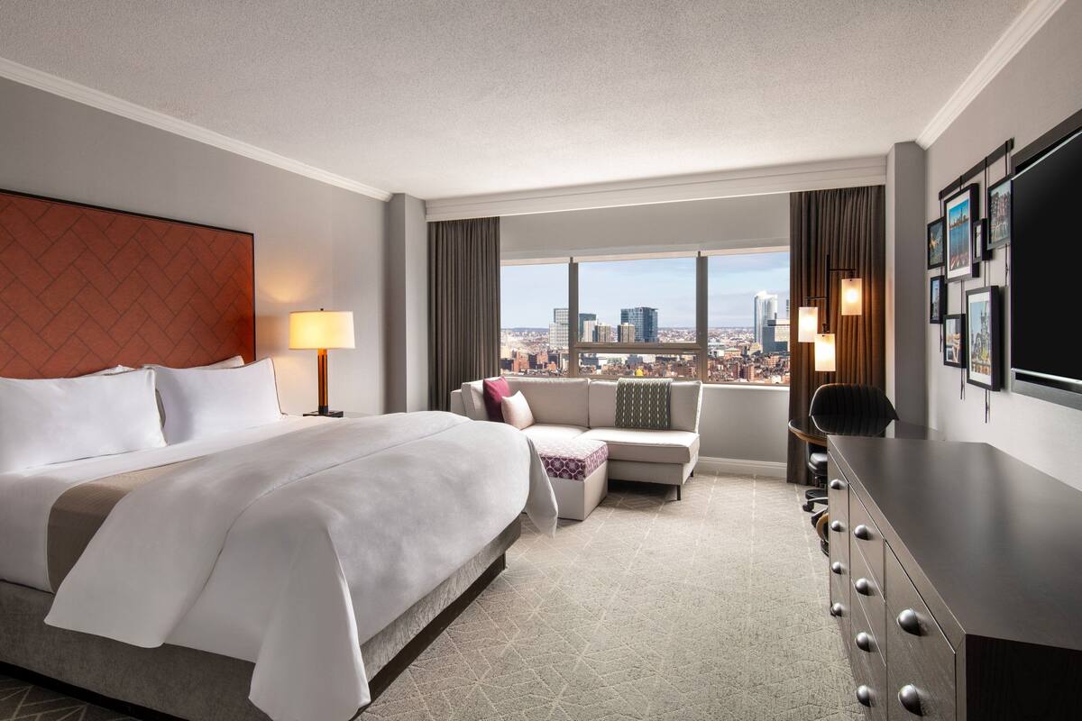 Una habitación de hotel con una cama grande, un sofá, un escritorio y vistas a la ciudad.