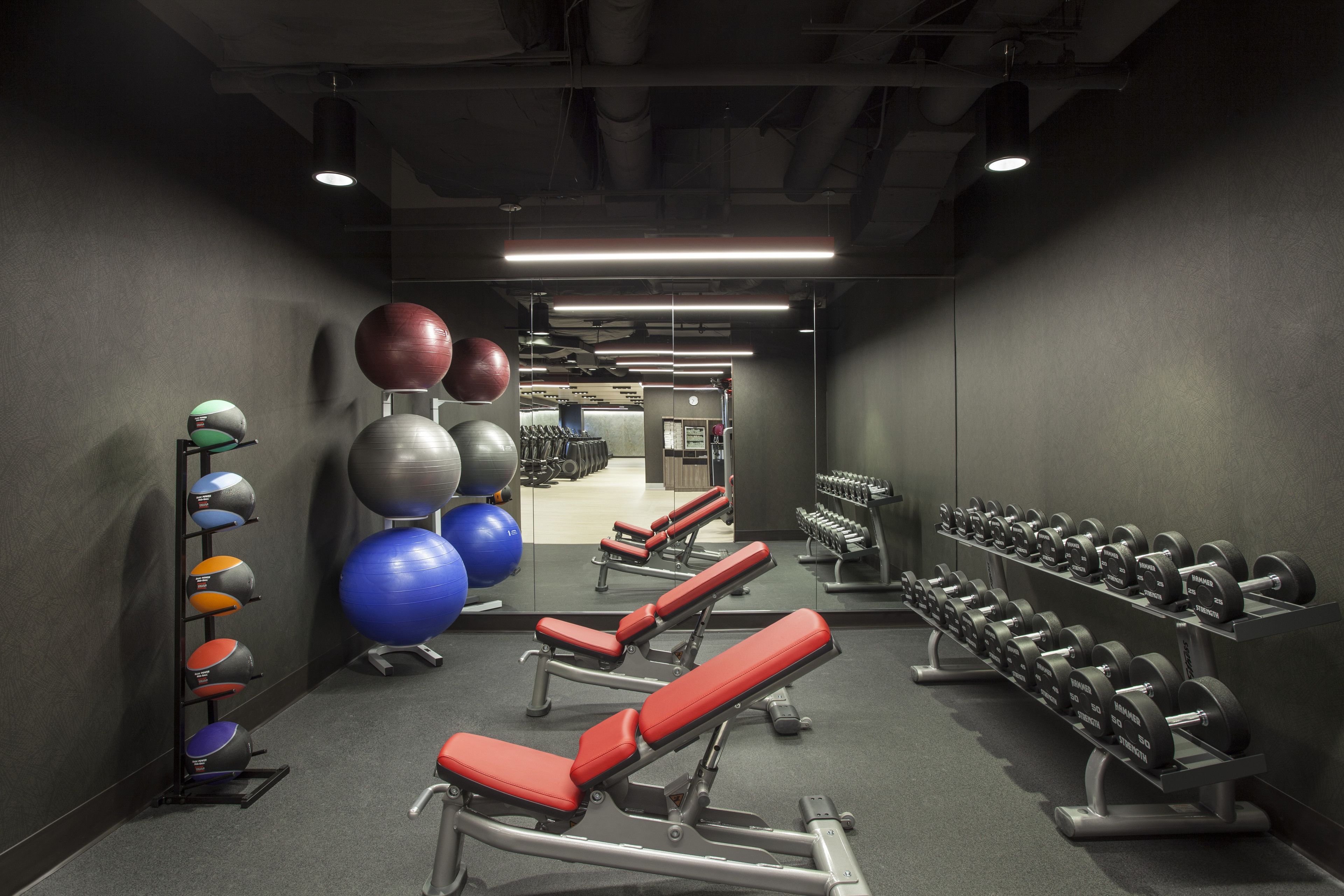 Een sportschool met trainingsapparatuur, banken en gewichten.