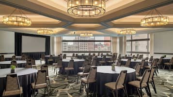 A conference room with round tables, chairs, and a large screen.