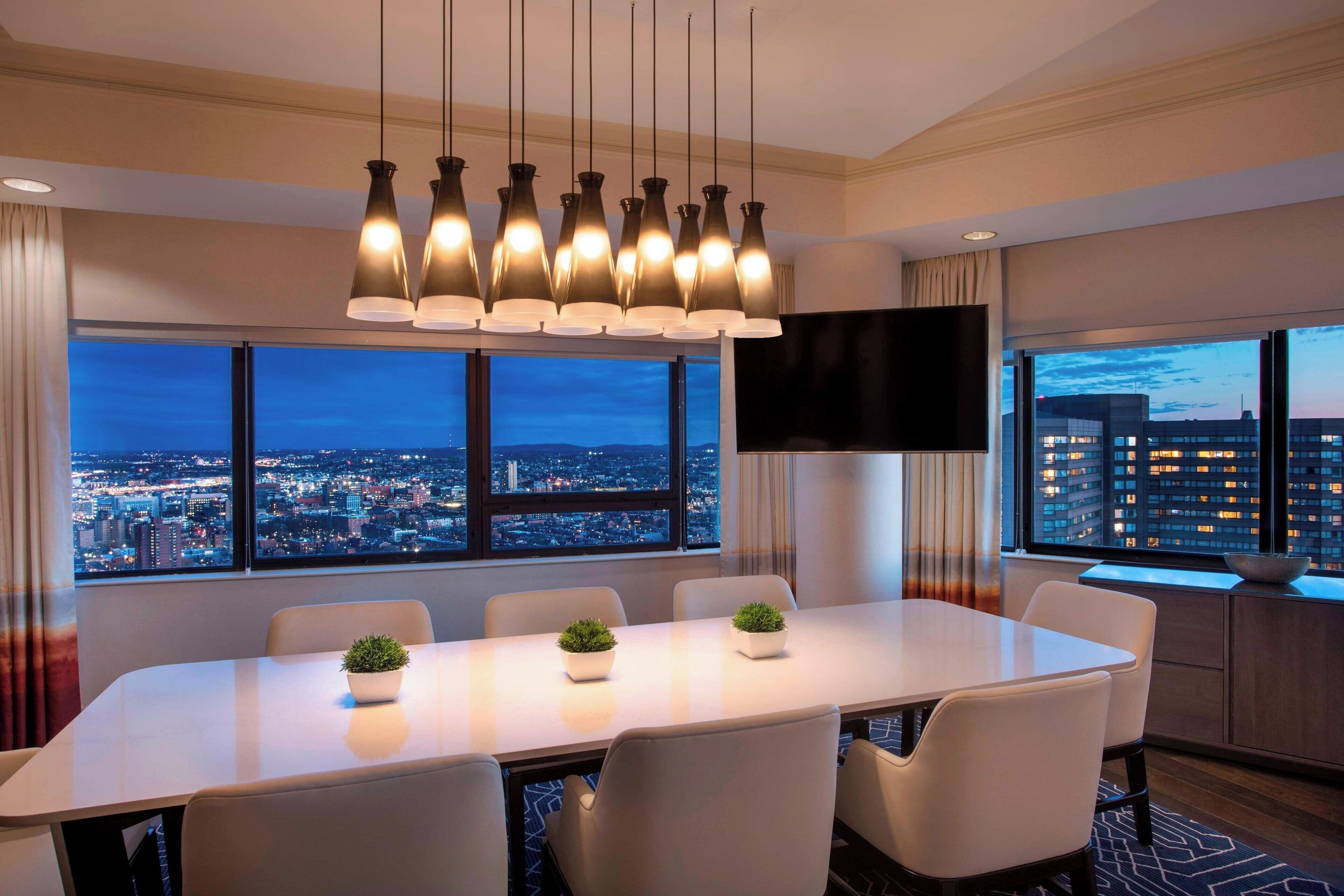 A modern conference room with a city view, a large table, and multiple chairs.