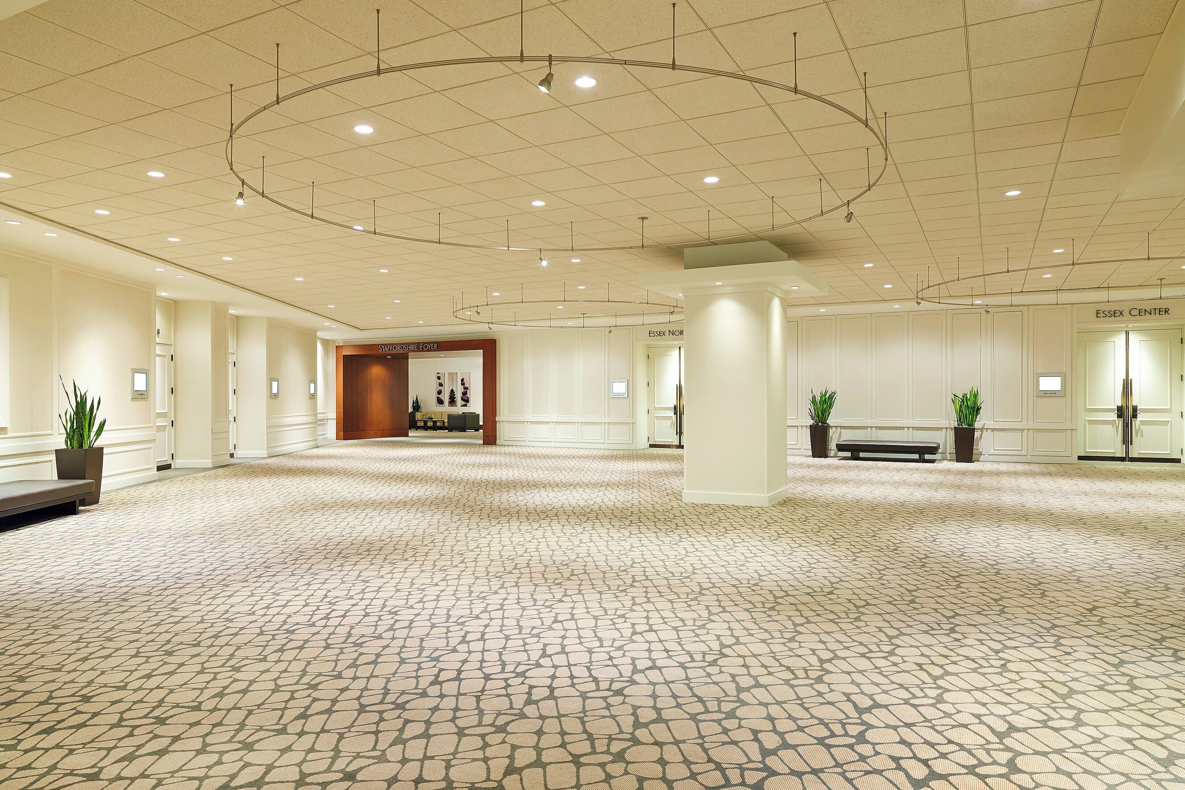 A spacious hall with a patterned floor, a central column, and a seating area with a bench.