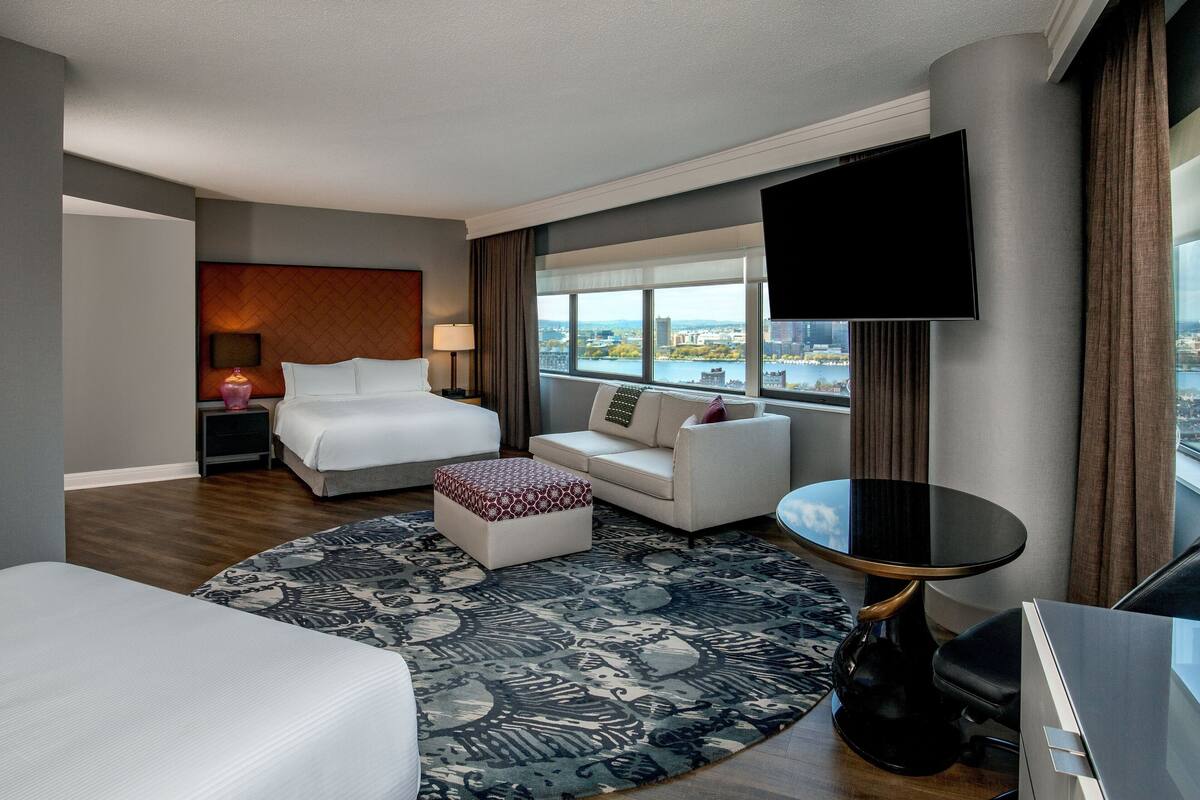 Una habitación de hotel con una cama, un sofá, un televisor y vistas a la ciudad.