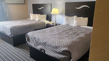 Een hotelkamer met twee bedden, een nachtkastje met een lamp en een telefoon.