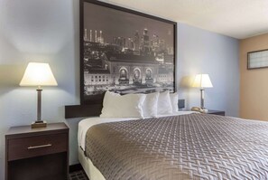 Habitación de hotel con una cama grande, dos mesitas de noche con lámparas, un cuadro de paisaje urbano en la pared y una ventana con persianas.