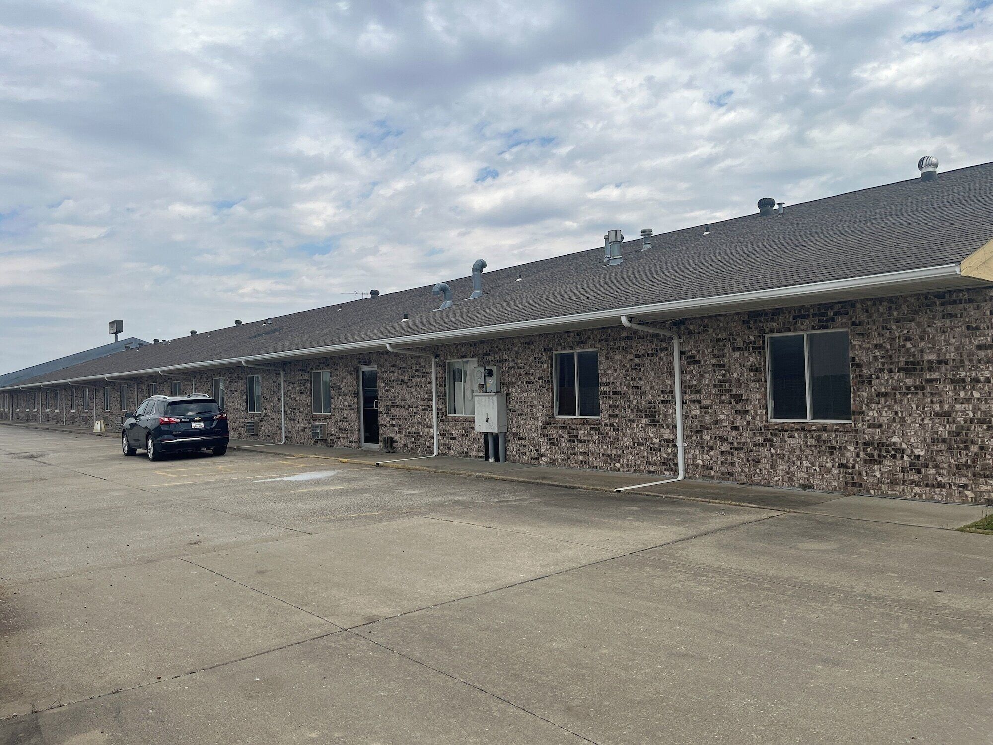 A row of motel rooms with a car parked in front.