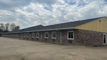 Una hilera de habitaciones de motel con ventanas individuales y un estacionamiento al frente.