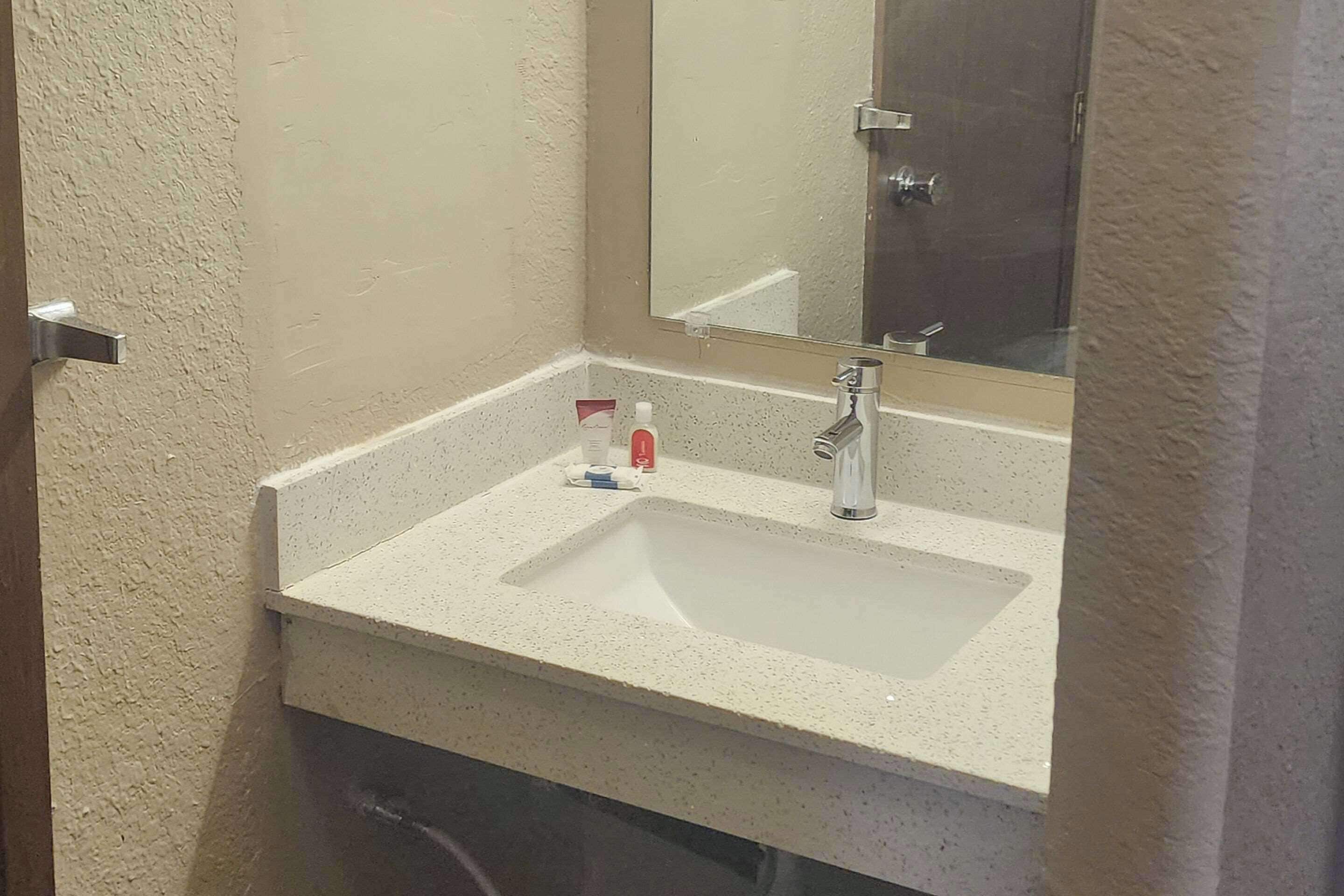 A bathroom with a white sink, a mirror, and a towel rack.
