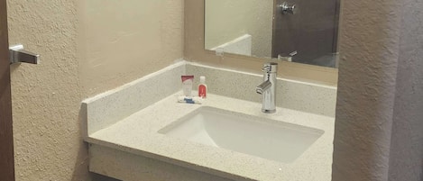A bathroom with a white sink, a mirror, and a towel rack.