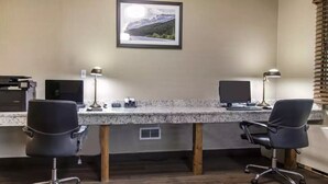 A dual desk setup with two chairs, a framed picture on the wall, and a window with blinds. - Flamingo Hotel (Medicine Hat)