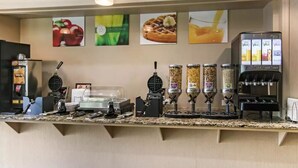 A breakfast bar with waffle makers, a coffee machine, and a juice dispenser. - Flamingo Hotel (Medicine Hat)