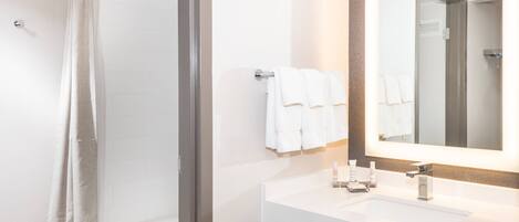 A modern bathroom with a shower, a sink with a mirror, and two towels hanging on the wall.
