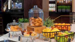 Un buffet de petit-déjeuner proposant des viennoiseries, des fruits et une machine à café.