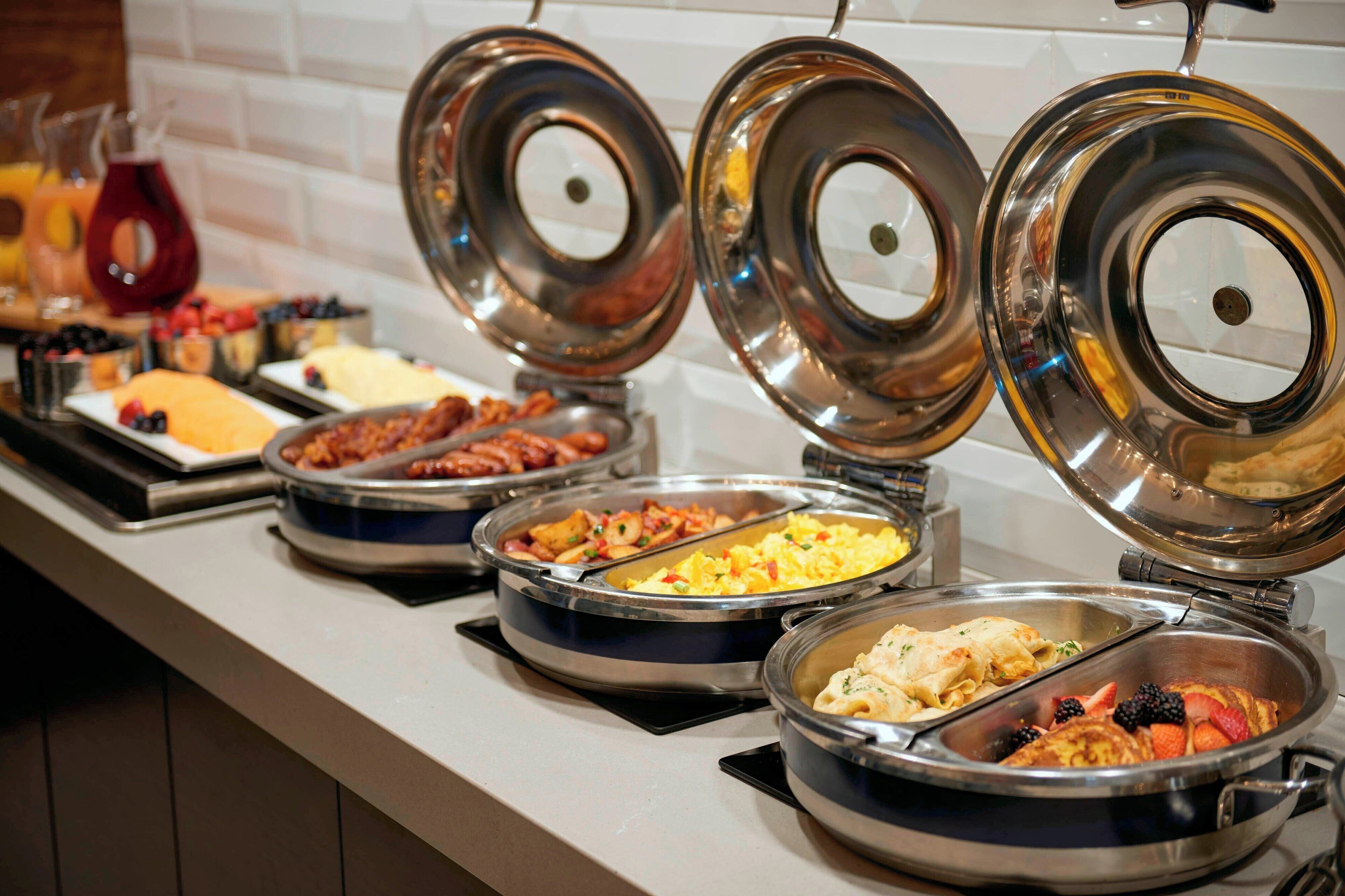 A buffet with various food options including fruits, eggs, and pasta.
