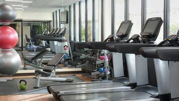 Un gimnasio con cintas de correr, balones de ejercicio y máquinas de pesas.