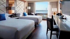 Une chambre d’hôtel avec deux lits, un bureau et une vue sur un plan d’eau.